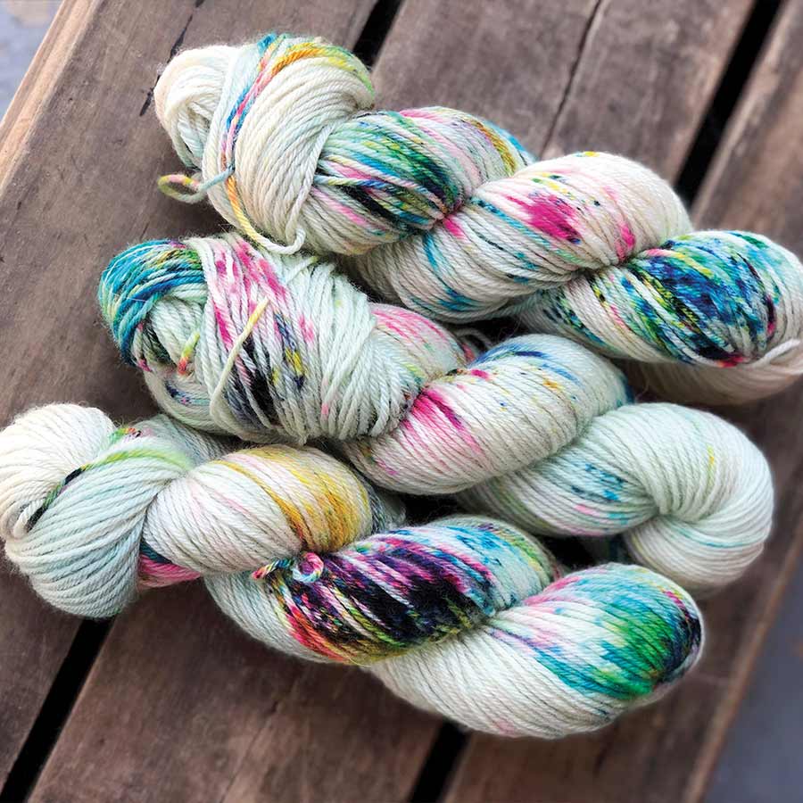 Jacquard Acid Dye Textilfarbe für Wolle und Seide Weiße Wollstränge mit bunten Farbsprenkeln auf Holz