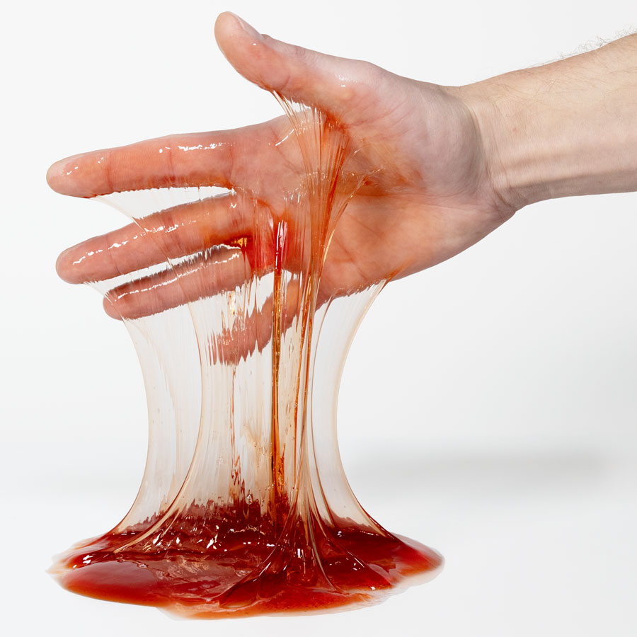 PATIN-SLIME Blutrot in der Hand Hand zieht Fäden aus PATIN-SLIME Blutrot, zähflüssiges Schleim-Effekt-Gel