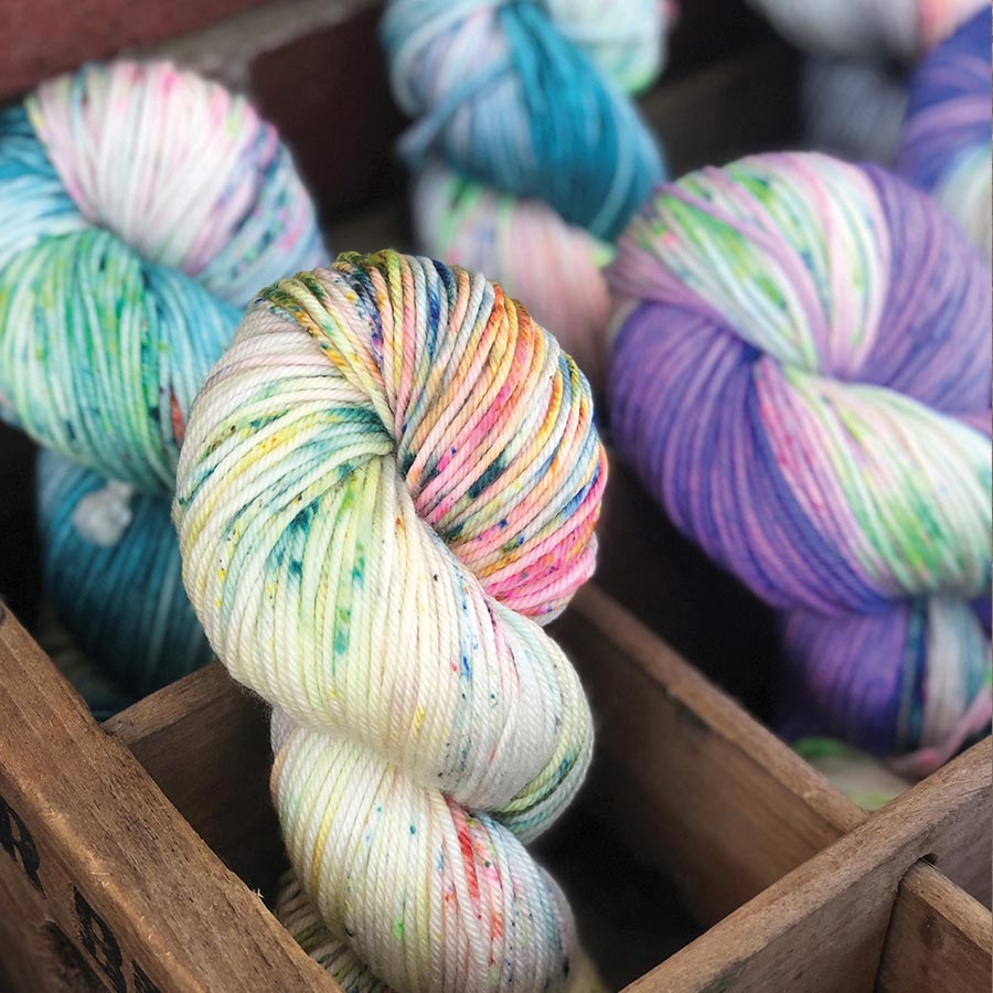 Jacquard Acid Dye Textilfarbe für Wolle und Seide Gesprenkelt gefärbte Wollstränge in Türkis, Weiß und Lila in einer Holzkiste