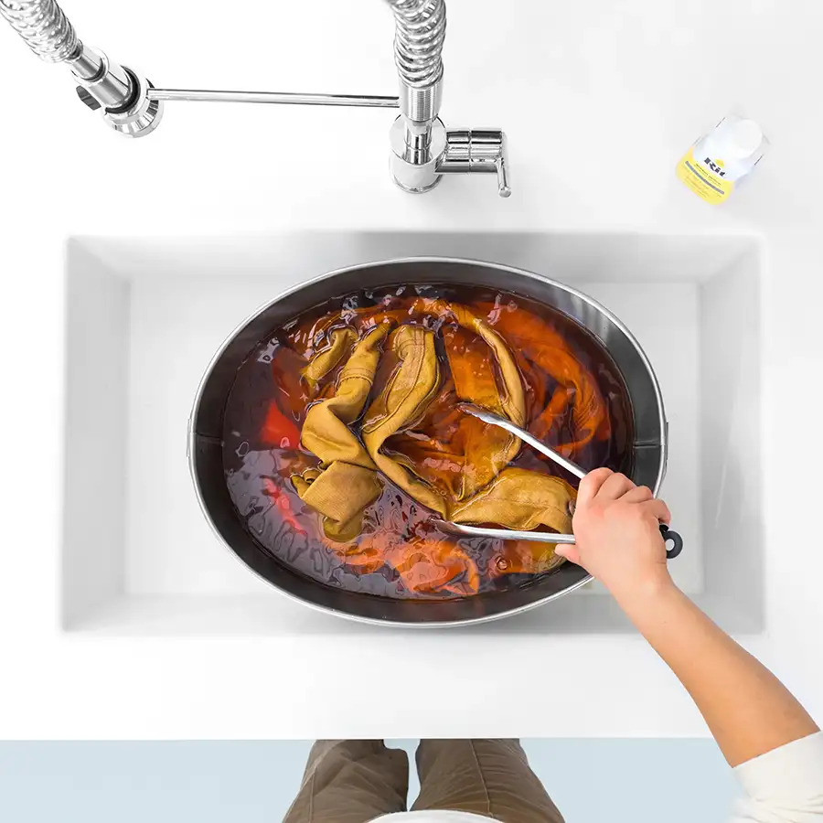 Rit All-Purpose Dye Universal Textilfarbe Kleidung wird in einer Schüssel im Spülbecken mit Rit All-Purpose Dye gelb gefärbt, Blick von oben